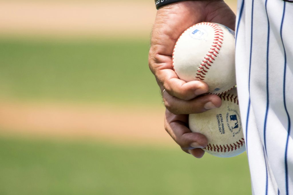 man holding two baseballs